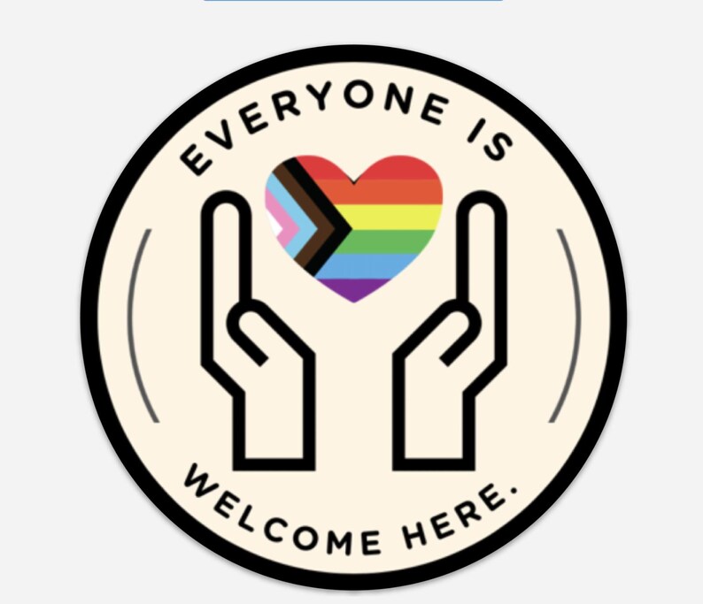 May include: A circular sticker with a cream background and a black border. It features a black line drawing of two hands cupping a heart filled with the Progress Pride flag colours. The text "EVERYONE IS WELCOME HERE." is printed in black.