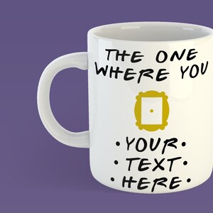 Puede incluir: Taza de cerámica blanca con un diseño en negro y dorado. La taza presenta el texto "THE ONE WHERE YOU" y un marco dorado con un punto en el centro. Debajo del marco, el texto dice ".YOUR. .TEXT. .HERE."