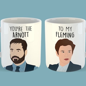 May include: Two white coffee mugs with black text and illustrations. The mug on the left says "You're the Arnott" and features a cartoon illustration of a man with brown hair and a beard. The mug on the right says "To my Fleming" and features a cartoon illustration of a man with brown hair.