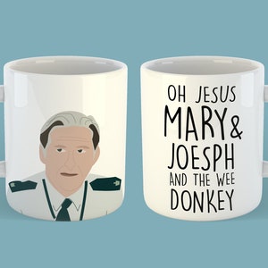 Op de afbeelding: Witte keramische mok met een cartoon illustratie van een man in uniform aan de ene kant en de tekst "OH JESUS MARY & JOESPH AND THE WEE DONKEY" aan de andere kant. De mok heeft een gebogen handvat en een lichtblauwe achtergrond.