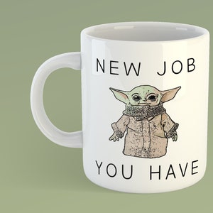 May include: White ceramic mug with a black and white graphic of a green alien character wearing a brown coat and scarf. The text "NEW JOB YOU HAVE" is printed on the mug.
