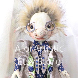 May include: A whimsical handmade doll with a unique design. The doll features a pale face, round glasses, and a fluffy hairstyle. It wears a blue star-patterned vest, a gray coat, and holds a small cane. The text "AforArtistic Etsy Store" is visible.