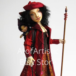 May include: A red-haired doll wearing a red dress and a red hat, holding a smaller doll in her arms. The larger doll is holding a wooden staff with a red and gold top.