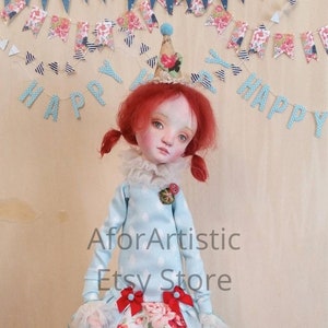 May include: A handmade doll with red hair wearing a blue and white polka dot dress with a floral print skirt and a party hat. The doll is standing on a blue and white platform with a banner that says "Happy Birthday".