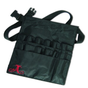 May include: Black makeup bag with multiple pockets and a belt loop. The bag has a red embroidered letter "A" with a crown on top.