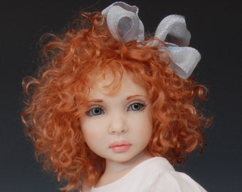 May include: A porcelain doll with red curly hair and a silver bow. The doll is wearing a white dress.