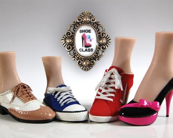 May include: A display of miniature shoes, including a brown and white oxford, blue canvas sneaker, red athletic shoe, and black and pink high heel. A decorative plaque with the text "SHOE CLASS" hangs in the background.