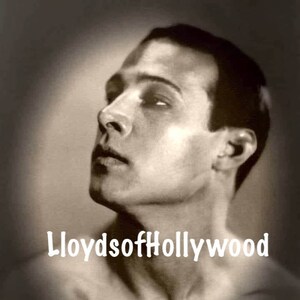 May include: Black and white portrait photograph of a man with short dark hair. The man is looking up and to the right. The photo is faded and has a vintage look. The text "LloydsofHollywood" is printed at the bottom of the photo.
