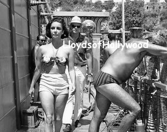 Elizabeth Taylor interpreta a Cleopatra. Su cuerpo queda al descubierto en un bikini de dos piezas. Fotografía espontánea e inédita tomada en el set en 1962.