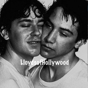 May include: Black and white photograph of two men embracing. Both men have dark hair and are wearing white t-shirts. The text "LloydsofHollywood" is printed in white at the bottom of the image.