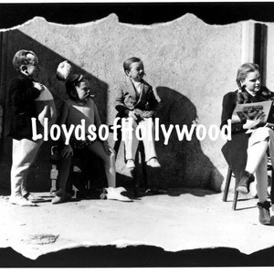 May include: A black and white photo of four children sitting on a bench. The children are wearing casual clothing and one child is holding a magazine. The magazine cover reads "LIFE".
