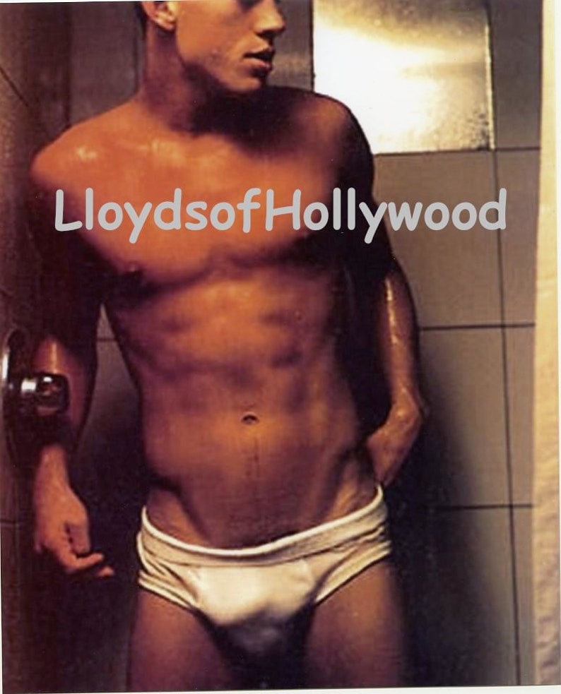 May include: A man in a shower wearing white briefs. The image has the text "LloydsofHollywood" in the upper center. The man is standing in a shower with a tiled wall.