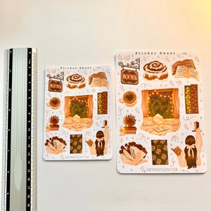 May include: A sticker sheet featuring a cosy, illustrated scene of a person reading a book in bed with a cup of coffee and a cinnamon roll. The sheet includes other illustrations such as books, a sign that says "BOOKS", and stars. The sheet is labelled "Sticker Sheet 295" and "ARTIMATION1104".