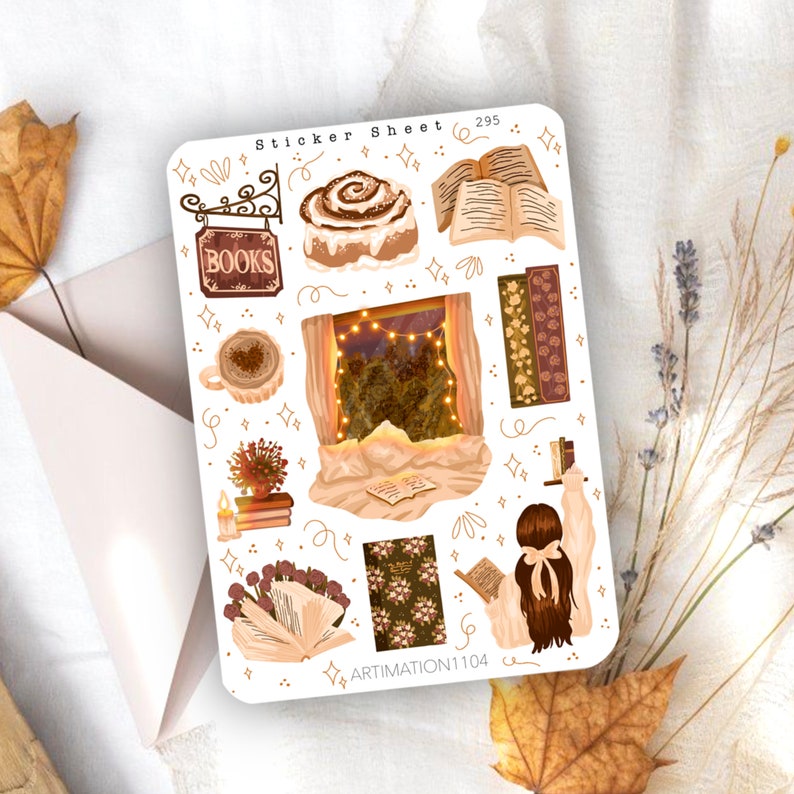 May include: A sticker sheet with a cosy autumn theme featuring illustrations of a cinnamon roll, books, a window with lights, a cup of coffee, a plant, and a person reading a book. The sheet also includes the text "Sticker Sheet 295" and "ARTIMATION1104".