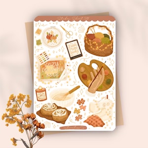 May include: A sticker sheet with a cozy autumn theme. It features illustrations of a pumpkin embroidery hoop, a basket of yarn, a palette with a hand holding a paintbrush, a coloring book, and cinnamon rolls. The text "Sticker Sheet 391" is at the top.
