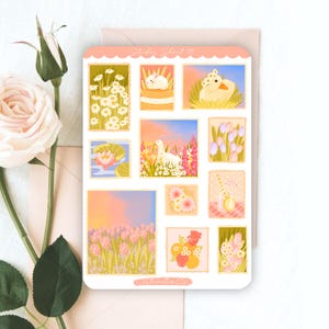 Peut inclure: Une planche d'autocollants rectangulaire pr&eacute;sentant diverses illustrations, notamment des marguerites blanches, un lapin blanc, un caneton jaune, un n&eacute;nuphar rose, une oie blanche dans un champ de fleurs, des tulipes roses et des compositions florales.