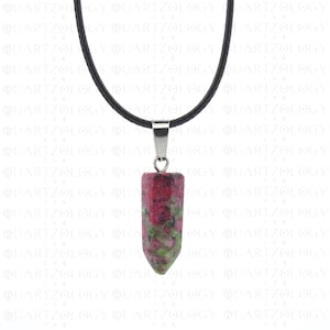 May include: A pendant necklace with a cylindrical gemstone, red and green in colour, and a pointed end. It hangs from a black cord with a silver-coloured metal clasp. The background has a repeating pattern of the word "QUARTZOLOGY".
