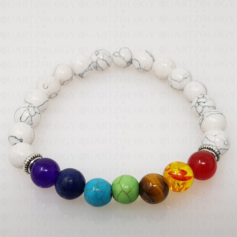 Puede incluir: Pulsera de cuentas blancas con siete piedras de chakra. Las piedras son amatista, lapisl&aacute;zuli, turquesa, aventurina verde, ojo de tigre, cornalina y jaspe rojo.