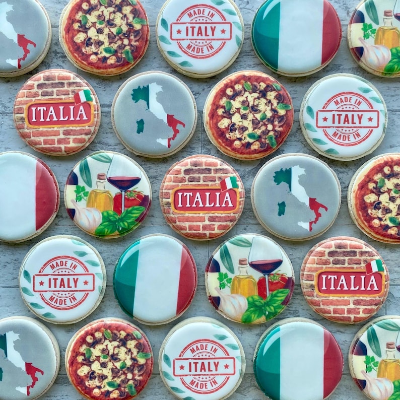 May include: A selection of round biscuits decorated with Italian themes. Some biscuits feature the Italian flag, pizza, or the word "ITALIA" on a brick background. Others have a map of Italy or the text "MADE IN ITALY".