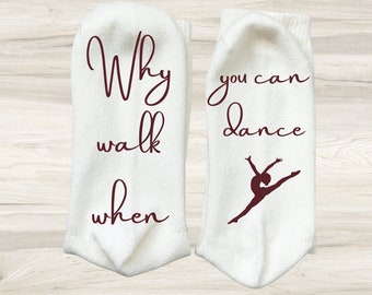 May include: A pair of white socks with maroon text. One sock says "Why walk when you can dance" and the other sock has a silhouette of a dancer.
