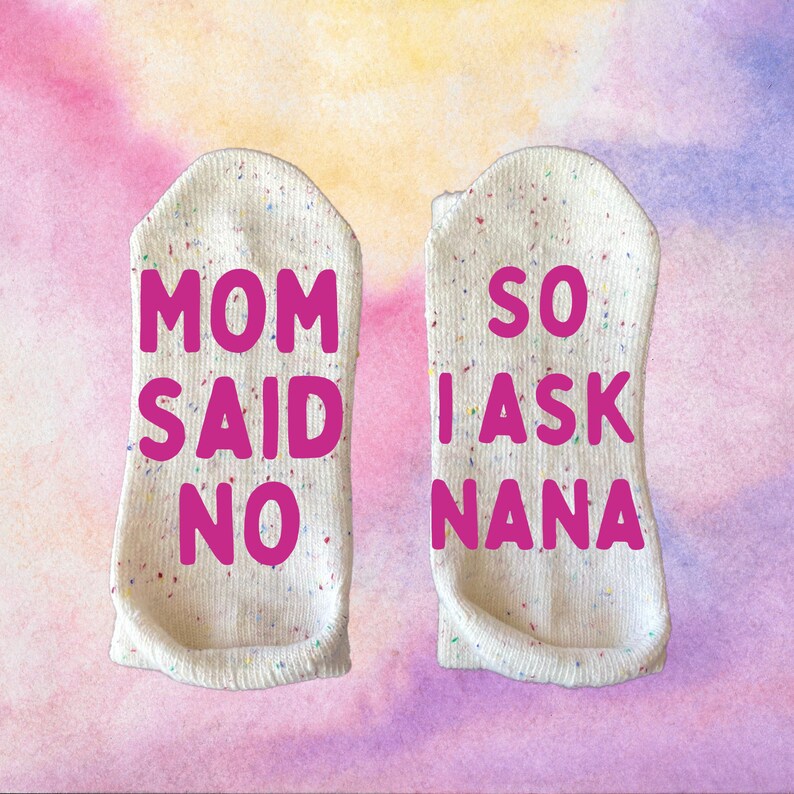 May include: A pair of white socks with colorful speckles. One sock says "Mom said no" and the other sock says "So I ask Nana".