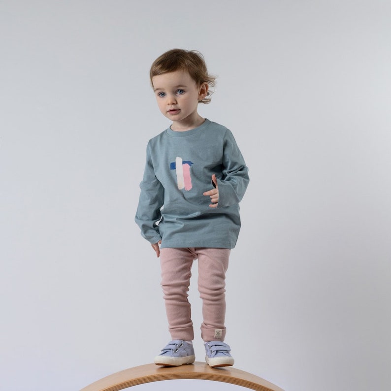 Young girl modelling the ribbed trousers from Aneby with rolled hem