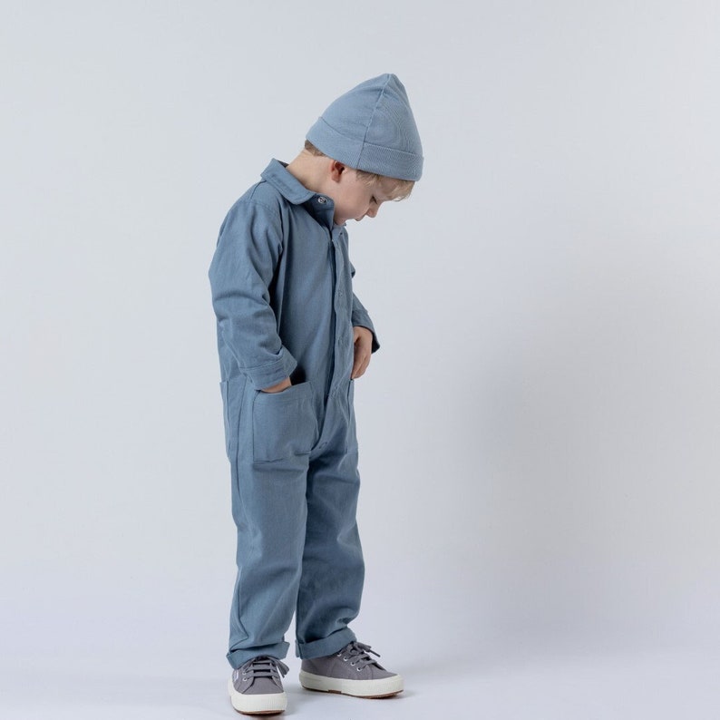 Young model wearing slate blue boiler suit with matching beanie