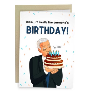 May include: A humorous birthday card featuring a cartoon illustration of a man in a suit smelling a birthday cake with the text "mmm... it smells like someone's BIRTHDAY!" and "*DEEP INHALE*" above the cake.