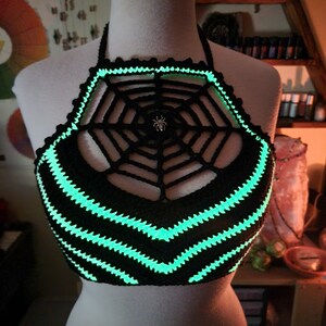May include: A black crocheted halter top with a glow-in-the-dark green spiderweb design and a silver spider charm.
