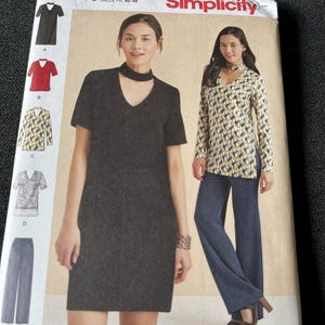 May include: A Simplicity 8425 sewing pattern envelope for sizes 12-20. The cover displays illustrations of a short-sleeved dress and a long-sleeved tunic with a choker-style neckline, alongside a pair of wide-leg trousers, showcasing various fabric options.