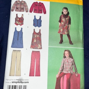May include: A Simplicity sewing pattern envelope 2484 for sizes K5 7, 8, 10, 12, 14. The package displays illustrations of a long-sleeve plaid jacket, a sleeveless vest, a sleeveless dress, and trousers, alongside photographs of children wearing the garments.