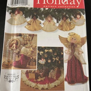 Może przedstawiać: Kolekcja wzorów Simplicity Holiday z ozdobami w kształcie aniołów i spódnicą choinkową. Wzór zawiera różne projekty, takie jak lalki aniołów ze złotymi skrzydłami i czerwonymi sukienkami oraz spódnicę choinkową z czerwoną podstawą i złotym wykończeniem.