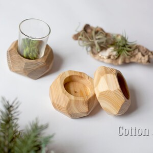 May include: Three wooden candle holders with geometric shapes. The holders are made of natural wood and have a light brown color. The holders are perfect for adding a touch of rustic charm to any home.
