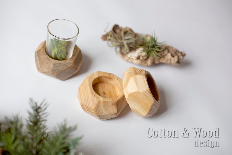 May include: Three wooden candle holders with geometric shapes. The holders are made of natural wood and have a light brown color. The holders are perfect for adding a touch of rustic charm to any home.