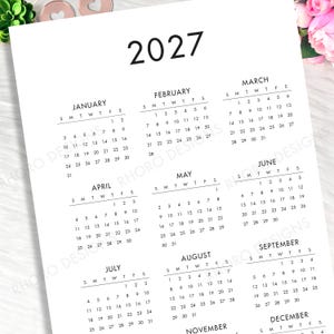 May include: A white paper 2027 annual calendar featuring black text and grid layouts for each month from January through December. The calendar displays the year 2027 at the top, followed by monthly grids organized with days of the week.