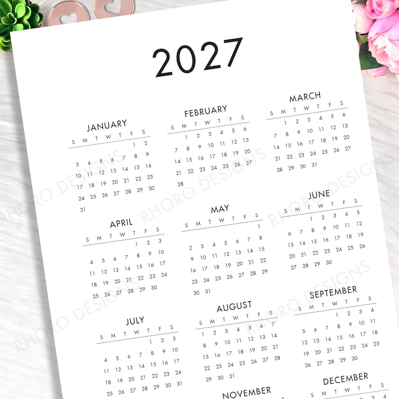 May include: A white paper 2027 annual calendar featuring black text and grid layouts for each month from January through December. The calendar displays the year 2027 at the top, followed by monthly grids organized with days of the week.