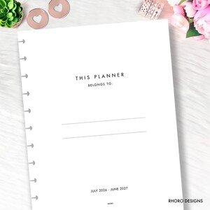 May include: A white disc-bound planner page with black text that reads THIS PLANNER BELONGS TO followed by two horizontal lines for writing. The bottom of the page displays the date range JULY 2026 - JUNE 2027 and the brand name RHORO DESIGNS.