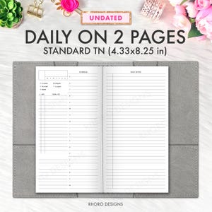 Puede incluir: Diario de cuero gris abierto con el texto "DAILY ON 2 PAGES" y "STANDARD TN (11 x 21 cm)". El diario está abierto a una página de planificador diario en blanco con un horario y una lista de tareas a la izquierda y notas con líneas a la derecha. La palabra "UNDATED" está en la parte superior.