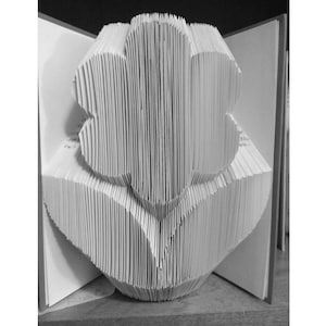 May include: A white paper flower sculpture made from the pages of a book. The flower is folded into a three-dimensional shape, with the pages forming the petals and leaves.