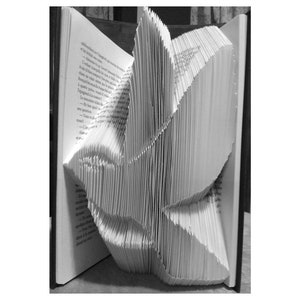 May include: A book with pages folded into a three-dimensional dove shape. The dove is made of white paper and is standing on a book.
