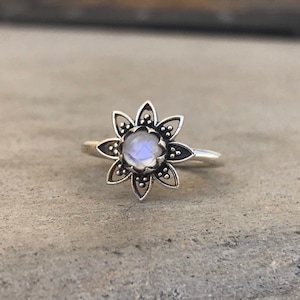 May include: A silver ring with a moonstone set in a flower design.