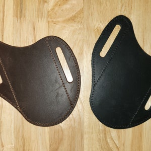 May include: Two leather holsters, one brown and one black, with stitching around the edges and two cutouts for belt loops.