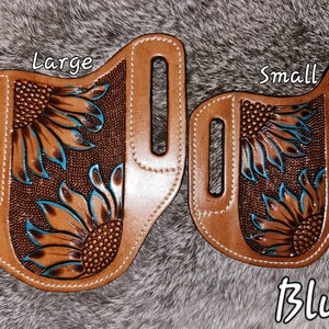 Puede incluir: Dos fundas de cuero con dise&ntilde;os de girasoles, una etiquetada como "Large" y la otra como "Small". Ambas fundas son marrones con detalles azules y el texto "Blue" es visible debajo de la funda m&aacute;s peque&ntilde;a.