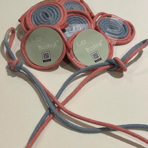 May include: A collection of pink and blue rope spools, some packaged. The rope is coiled and presented with circular cardboard tags bearing the text "Leo Board" and a QR code. Two strands of the rope are knotted together.