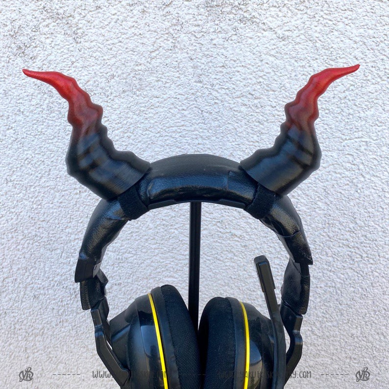 May include: Black gaming headphones with red and black devil horns attached to the headband.