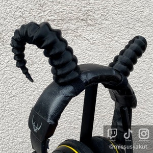 Peut inclure: Casque audio noir avec un design de bandeau noir texturé unique. Le bandeau est doté de deux cornes noires texturées et incurvées. Le casque est doté d'un écouteur noir rembourré et d'un bandeau noir réglable.