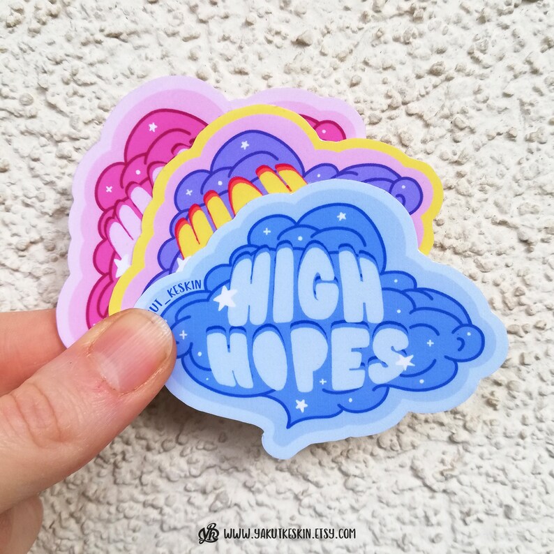 Puede incluir: Tres pegatinas de nubes de color pastel con un patr&oacute;n de estrellas blancas. La pegatina de abajo es azul y dice "HIGH HOPES" en una fuente caprichosa.