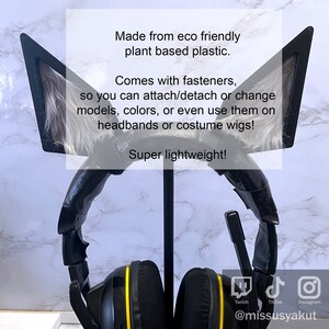May include: Black cat ear headphones with faux fur on the ears. The headphones are on a stand and have yellow accents. The text on the image reads: "Made from eco friendly plant based plastic. Comes with fasteners, so you can attach/detach or change models, colors, or even use them on headbands or costume wigs! Super lightweight!"  The image also includes social media icons for Twitch, TikTok, and Instagram, and the text "@missusyakut".