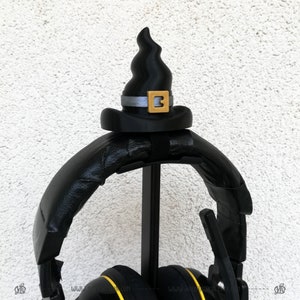 May include: Black headphones with a black witch hat on top. The hat has a gold buckle with the number "3" on it.