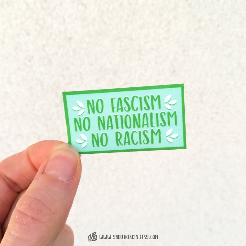 K&ouml;nnte beinhalten: Ein hellblauer Aufkleber mit gr&uuml;nen R&auml;ndern und wei&szlig;em Text, der "NO FASCISM NO NATIONALISM NO RACISM" lautet.